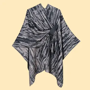 Close-up of knit shawl poncho featuring V-neckline and decorative front buckle