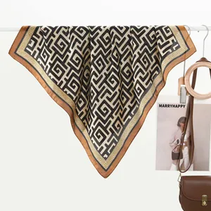 Close-up of a satin scarf with black and caramel geometric maze patterns and Greek key borders