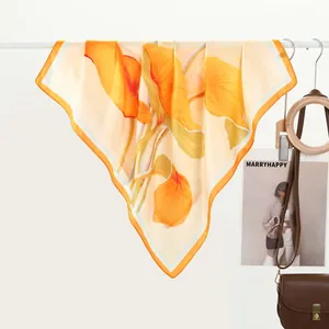 Detail of vibrant orange floral print silk scarf hanging with smooth glossy texture