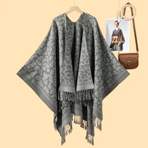 Classic grey leopard print knitted poncho with tassel fringe on a wooden hanger