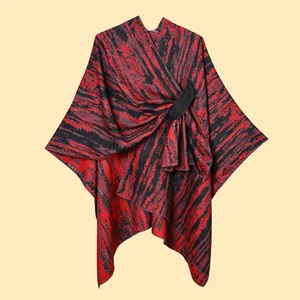 Close-up of knit poncho with abstract red and black patterns and circular metal buckle