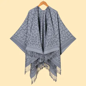 Detail of grey leopard print shawl with fringe hem hanging on a wooden hanger