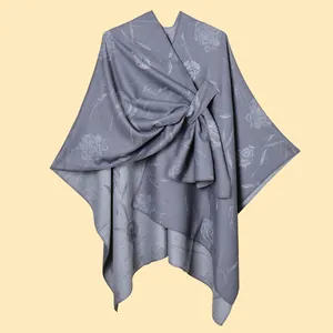 Dettaglio dello scialle grigio in maglia con jacquard floreale e drappeggio a nodo
