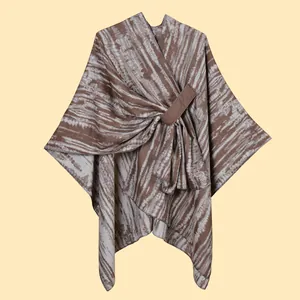 Detail of knitted poncho wrap with brown and beige stripes and a front buckle closure