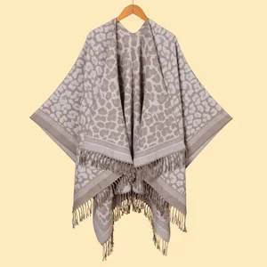 Detailed close-up of grey leopard print shawl with fringe hem on a wooden hanger