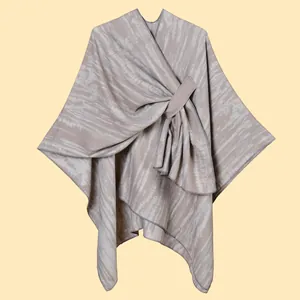 Close-up of beige knit shawl with soft ripple texture and asymmetric drape detail