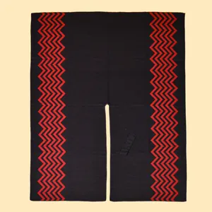 Detail of black knit shawl with red wave patterns and a front slit drawstring closure