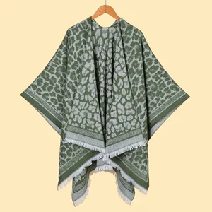 Close-up of jacquard leopard print knit shawl with white fringe details and green pattern