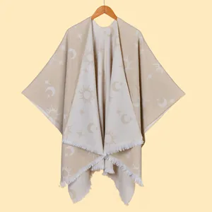 Detail of knitted beige shawl featuring sun moon jacquard pattern and white fringe trim