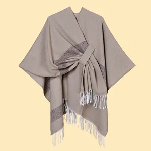 Detail of light camel knit shawl featuring tassel fringe and contrast stripe edges