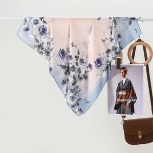 Elegant silk-like scarf with blue rose print and pink to blue gradient displayed on a rack