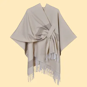 Detail of beige wrap shawl with brown stripes featuring a tassel fringe and crossover design