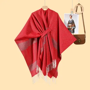 Detailed texture of red knitted shawl featuring grey stripes and thick white fringe tassels