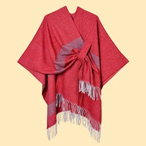 Close-up of red knitted shawl with grey stripes, waist tie and white tassel hem details