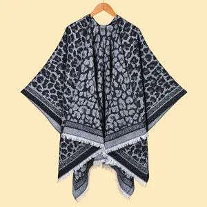 Detail of grey leopard knit shawl featuring soft texture and white fringe tassels