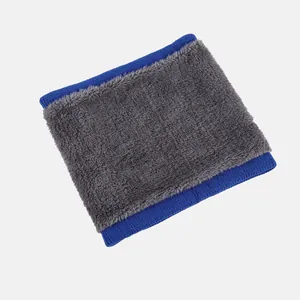 Detailed view of winter neck warmer featuring dark grey plush fabric and blue ribbed edges
