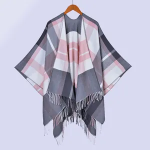 Detail of pink and grey plaid shawl with soft fringe trim hanging on a wooden hanger