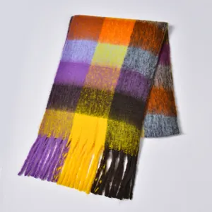 Macro detail of rainbow plaid scarf showing thick bouclé yarn texture and long fringe