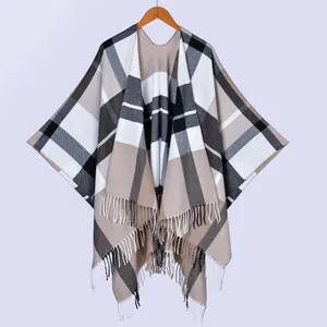 Detailed close-up of beige plaid shawl cape with soft tassels and woven texture details
