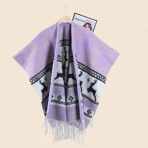 Détail du poncho de Noël avec motifs de rennes, flocons de neige et bords frangés