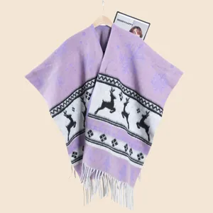 Détail d'un châle en tricot d'hiver avec motifs de flocons, rennes et longues franges