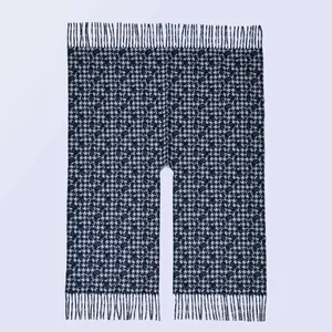 Detailansicht eines schwarz-weißen Hahnentritt-Ponchos mit Fransen und gewebter Textur