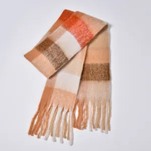 Detail of soft rainbow plaid scarf featuring orange and coffee tones with long tassels