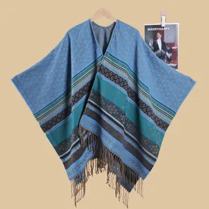 Detail of bohemian knit shawl with geometric patterns and fringe hem on wooden hanger