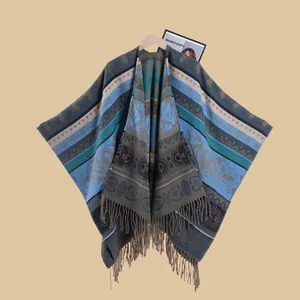 Detail of bohemian jacquard poncho showing paisley patterns and fringe hem on wooden hanger