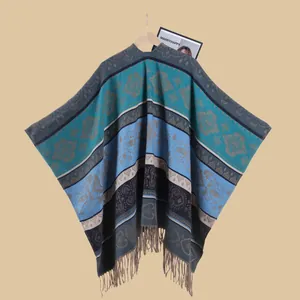 Detail of ethnic jacquard knit poncho with turquoise floral patterns and fringe edges