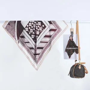 Détail d'un foulard carré en satin avec des motifs géométriques et des tons marron