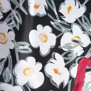 Detail of silk scarf showing abstract white floral print with orange spiral and red rolled edges