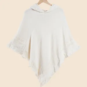 Gros plan du poncho tricoté beige à capuche avec ourlet à franges et motifs ajourés