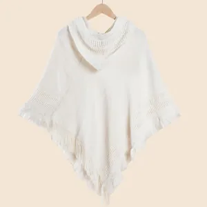 Détail du poncho en tricot blanc à capuche montrant les motifs de vagues et franges