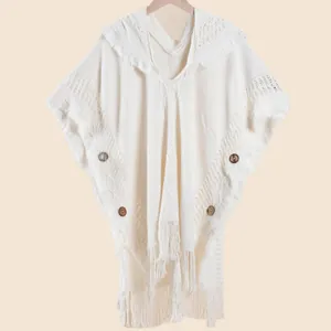 Detail of bohemian cream knit hooded shawl featuring decorative tassels and wooden buttons