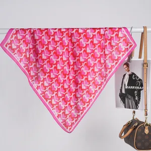 Détail d'un carré de soie rose avec motifs de cœurs et bordure satinée élégante