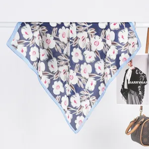 Detail of blue silk scarf featuring white floral prints and light blue hem borders