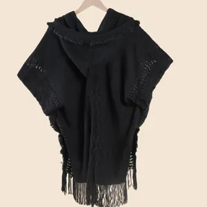 Detail of cable knit pattern and fringed edges on a black hooded winter travel shawl