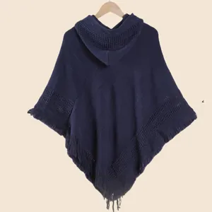 Détail d'un poncho en maille marine avec capuche, pompons et motifs ajourés