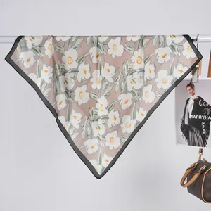 Detail view of pink silk scarf with floral print and black border on a hanger