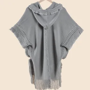 Close-up of light gray knitted shawl featuring fringe edges and diamond patterns