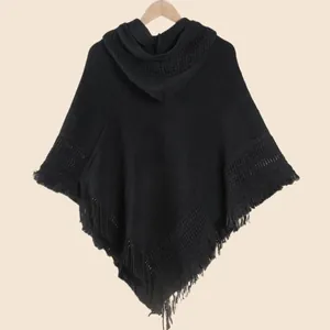 Détail d'un poncho noir à capuche avec bordure à franges et texture maille alvéolée