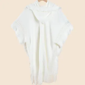 Detail of white hooded knit shawl showing intricate crochet patterns and long fringe edges