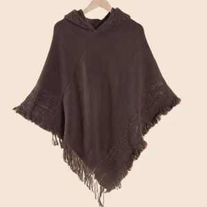 Détail d'un poncho en maille marron café avec des coutures texturées et des franges