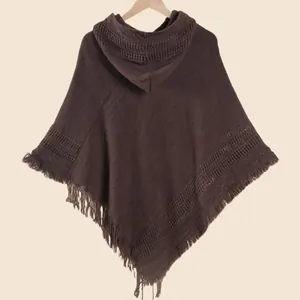 Détail d'un poncho en tricot marron foncé montrant des franges et un tissu doux à capuche
