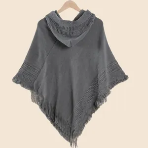 Détail d'un poncho à capuche en maille gris foncé avec franges et motifs texturés