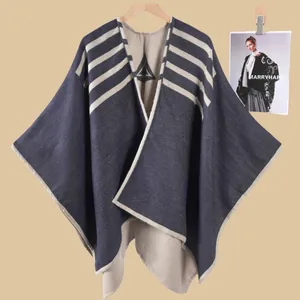 Dettaglio poncho in maglia blu scuro con strisce beige e motivo geometrico morbido