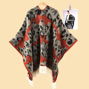 Detailaufnahme von Strickponcho mit Leopardenmuster, roten Schleifen und weißen Fransen
