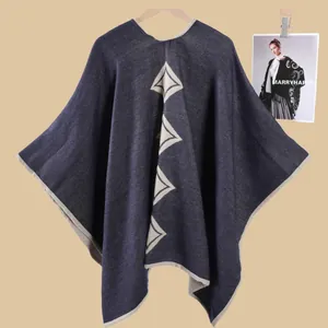 Dettaglio poncho in maglia blu navy con rombi bianchi e bordi arrotolati beige