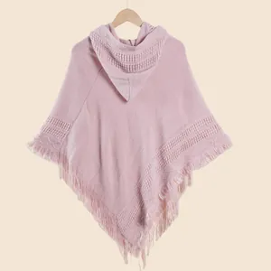 Détail du poncho en tricot rose montrant la texture rayée et les longues franges